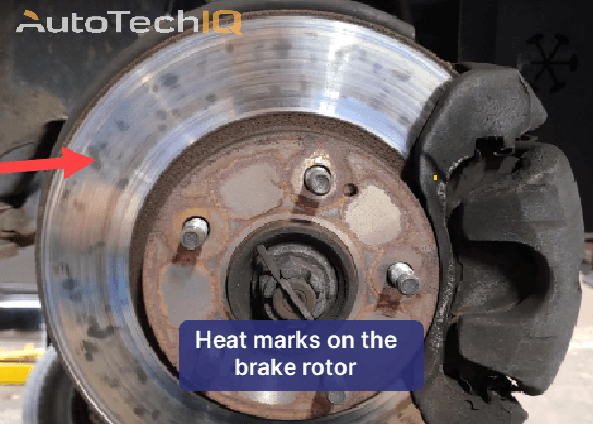 The brake rotor is showing heat marks due to overheating and wear